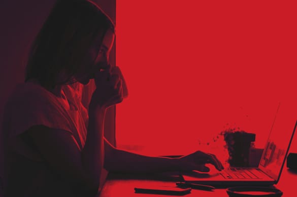 woman sitting at laptop with cup of coffee